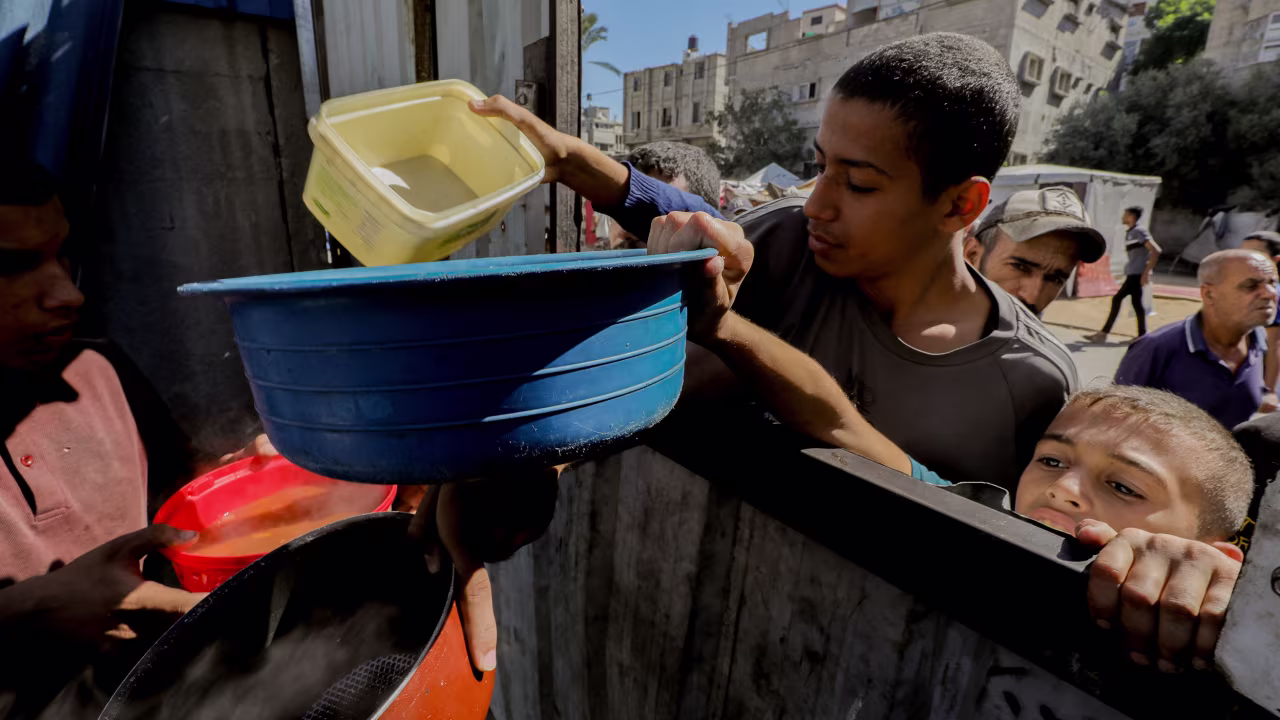 Children reach out with bowls during a food distribution in Gaza City on October 21.
