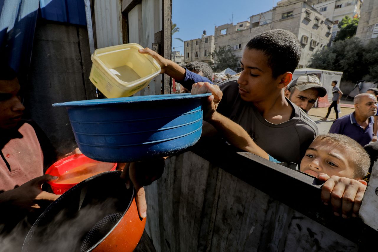 Children reach out with bowls during a food distribution in Gaza City on October 21.