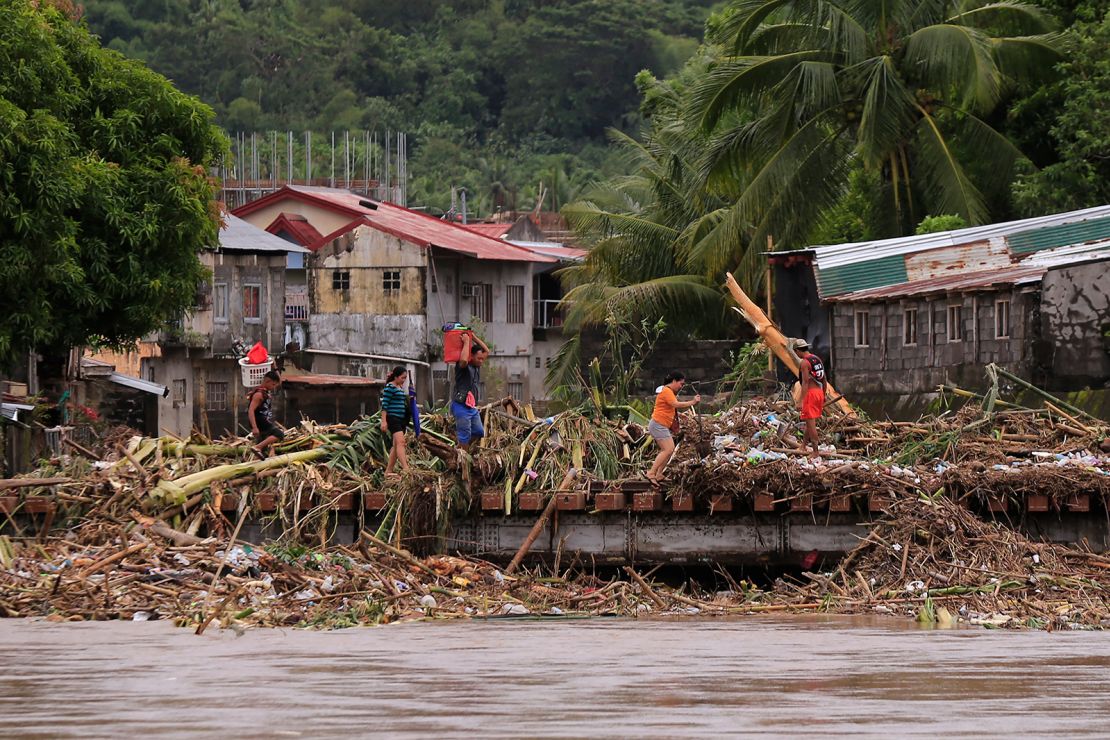 Residents cross a bridge filled with debris due to heavy rains brought about by Tropical Storm Trami in Polangui town, Albay province South of Manila on October 23, 2024.