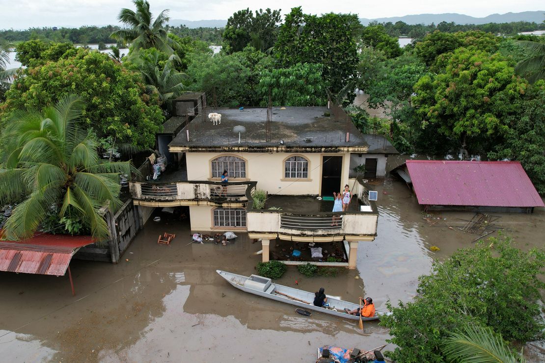 An aerial view shows a resident aboard a wooden boat maneuvering past flooded houses caused by Tropical Storm Trami in Bato town, Camarines Sur province South of Manila on October 23, 2024.