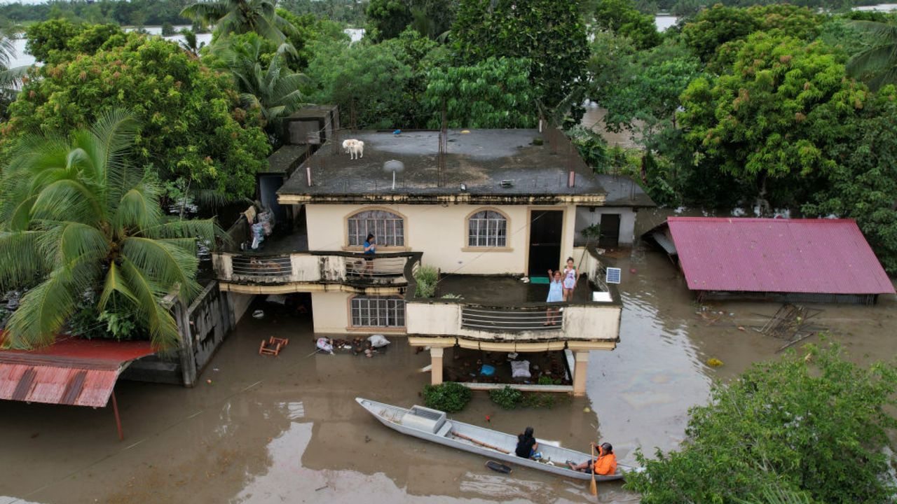 An aerial view shows a resident aboard a wooden boat maneuvering past flooded houses caused by heavy rains brought about by Tropical Storm Trami in Bato town, Camarines Sur province South of Manila on October 23, 2024. Torrential rains driven by the storm have turned streets into rivers, submerged entire villages and buried some vehicles up to their door handles in volcanic sediment knocked loose by the downpour. (Photo by CHARISM SAYAT / AFP) (Photo by CHARISM SAYAT/AFP via Getty Images)