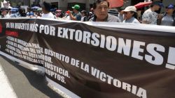 A protester holds a banner demanding to stop extortions in front of the Congress building in Lima during a strike called by transport workers and traders on October 23, 2024, demanding action from the government against a growing wave of extortion and murders by organized crime. Hundreds of truckers and merchants held protest marches in Peru on Wednesday against a wave of extortion and murders by organized crime. (Photo by Cris BOURONCLE / AFP) (Photo by CRIS BOURONCLE/AFP via Getty Images)