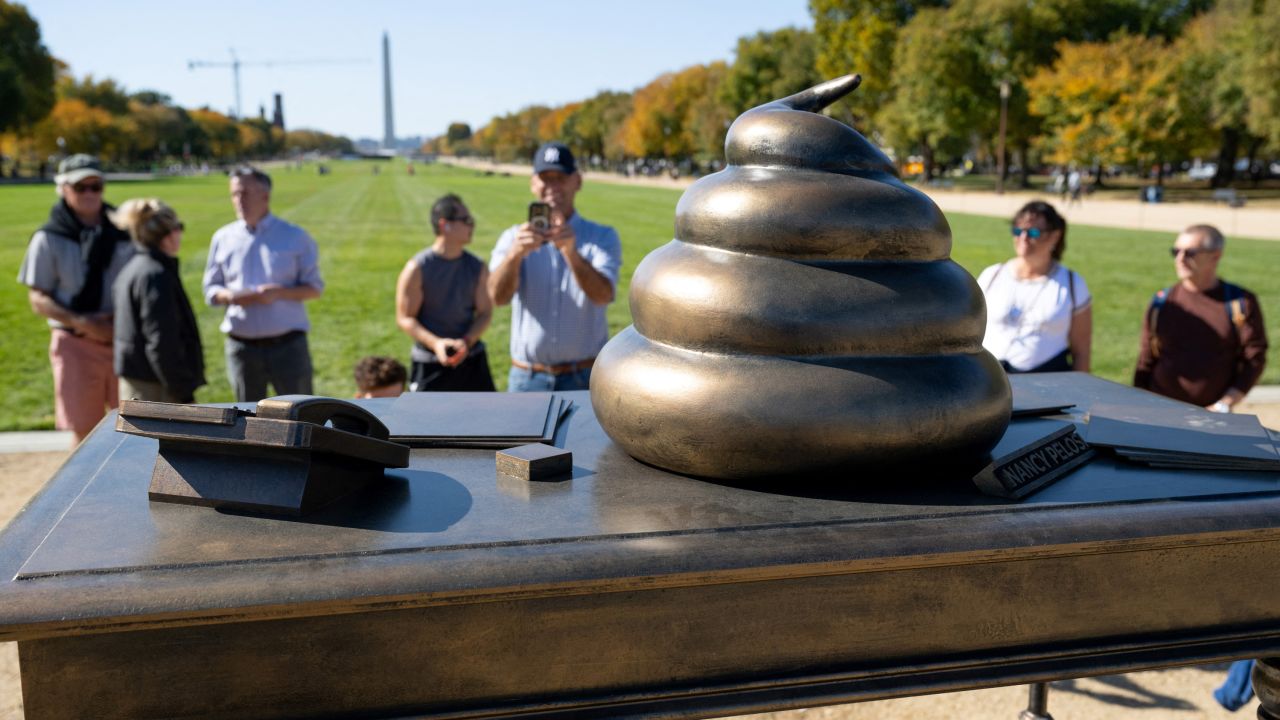 People look at a bronze art installation depicting a pile of feces on former US Speaker of the House Nancy Pelosi's desk that is made to look like a monument by the group Civic Crafting to protest remarks by former US president and Republican presidential candidate Donald Trump's comments honoring the January 6, 2021 attack on the US Capitol, on the National Mall near the US Capitol in Washington, DC, on October 24, 2024. (Photo by SAUL LOEB / AFP) (Photo by SAUL LOEB/AFP via Getty Images)