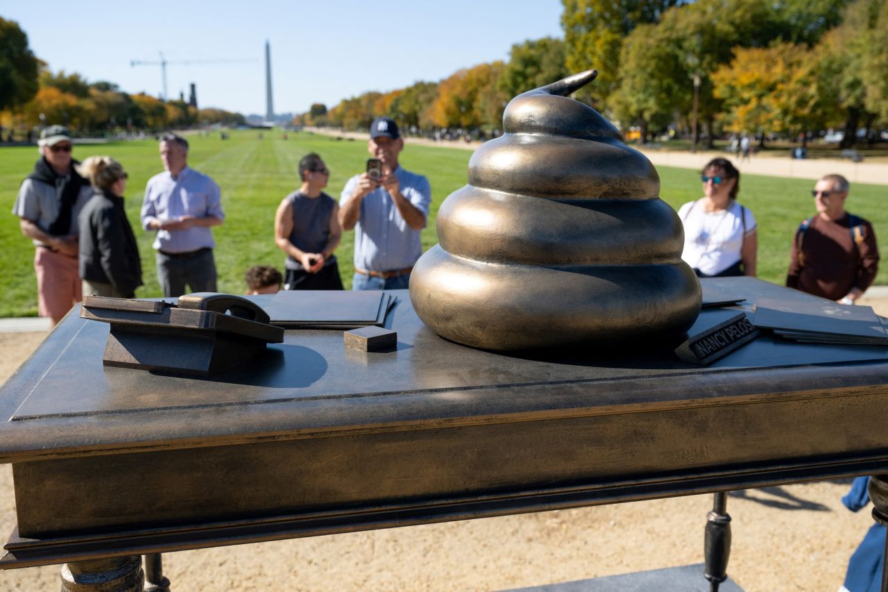 People look at a bronze art installation depicting a pile of feces on former US Speaker of the House Nancy Pelosi's desk on the National Mall near the US Capitol in Washington, DC, on October 24, 2024.