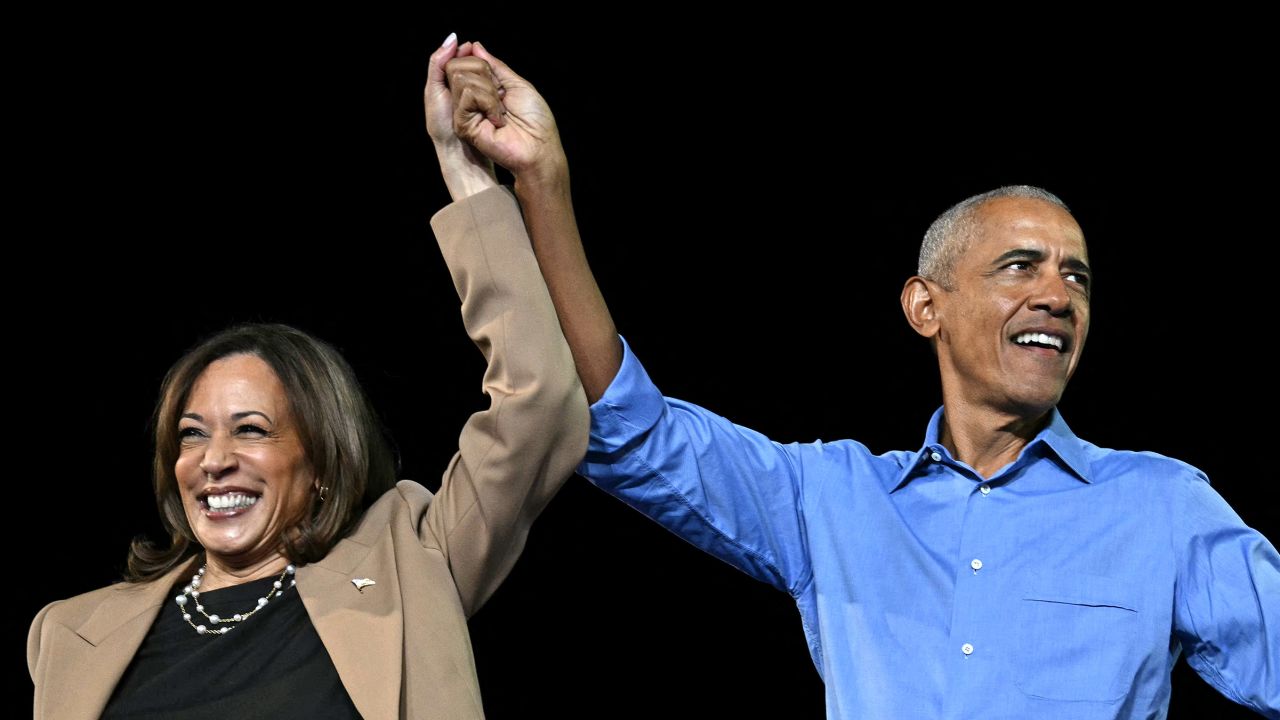 Former President Barack Obama hold hands with Vice President and Democratic presidential candidate Kamala Harris during a campaign rally at the James R Hallford Stadium in Clarkston, Georgia on October 24, 2024.