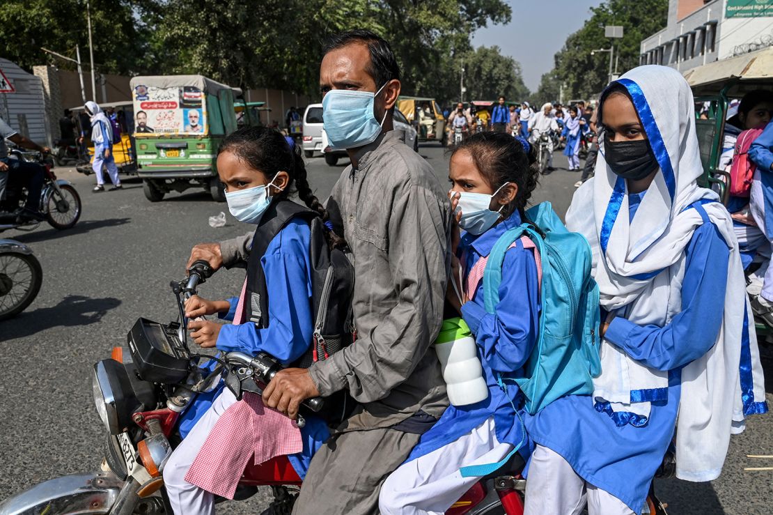 Schoolgirls wearing masks ride a motorcycle as they leave school amid a rise in smog levels in Lahore, Pakistan on October 25, 2024.