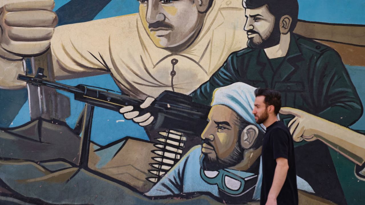 A man walks past a mural painting in a street in Tehran on October 26, 2024. Residents of Tehran awoke and went about their business as planned on October 26 after their sleep was troubled by Israeli strikes that triggered blasts that echoed across the city. (Photo by ATTA KENARE / AFP) (Photo by ATTA KENARE/AFP via Getty Images)