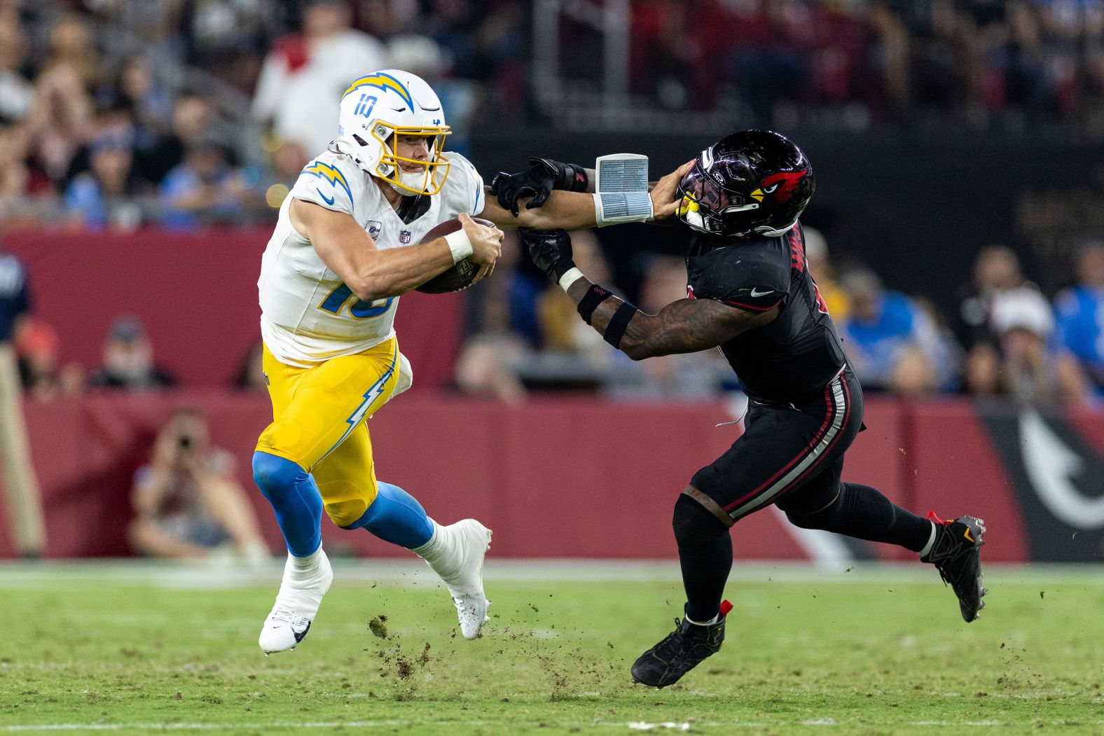 Los Angeles Chargers quarterback Justin Herbert stiff arms Arizona Cardinals linebacker Mack Wilson Sr. during the Chargers' 17-15 loss in Glendale, Arizona, on Monday, October 21.