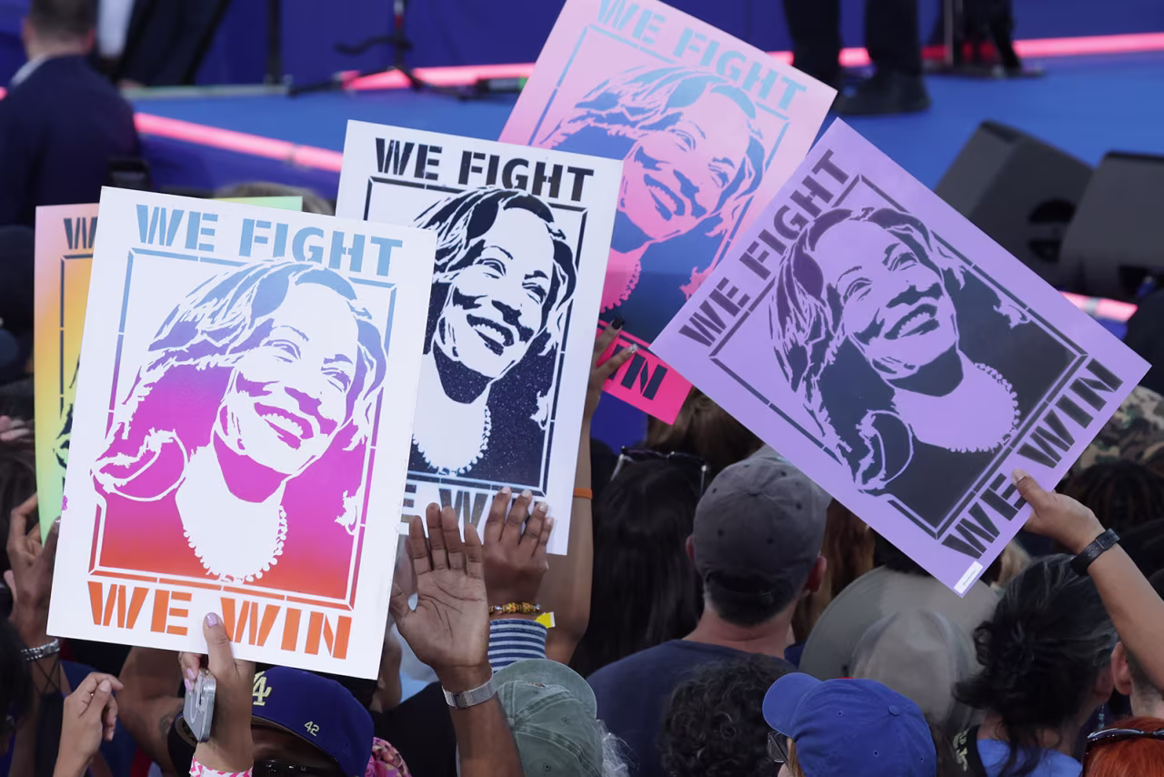 Supporters of Democratic presidential nominee Vice President Kamala Harris, hold signs during a campaign event with former President Barack Obama at the James R Hallford Stadium in Clarkston, Georgia, on October 24, 2024.