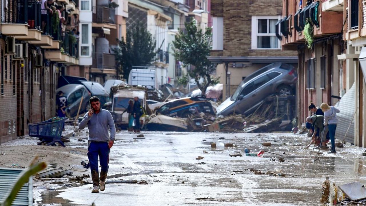 TOPSHOT - Residents are pictured next to cars piled in a street covered in mud following floods in Picanya, near Valencia, eastern Spain, on October 30, 2024. Floods triggered by torrential rains in Spain's eastern Valencia region has left 51 people dead, rescue services said on October 30. (Photo by Jose Jordan / AFP) (Photo by JOSE JORDAN/AFP via Getty Images)