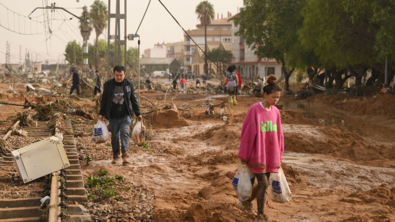 VALENCIA, SPAIN - OCTOBER 30: People walk along train tracks covered debris after flash-flooding hit the region on October 30, 2024 in Valencia, Spain. Spanish authorities said on Wednesday that at least 52 people had died in the Valencia region overnight after flash-flooding followed heavy rain. Spain's meteorological agency had issued its highest alert for the region due to extreme rainfall. (Photo by David Ramos/Getty Images)