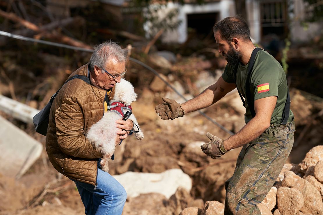 A man carries a dog after flash floods hit the region in Letur, Albacete province, Spain on October 30, 2024.