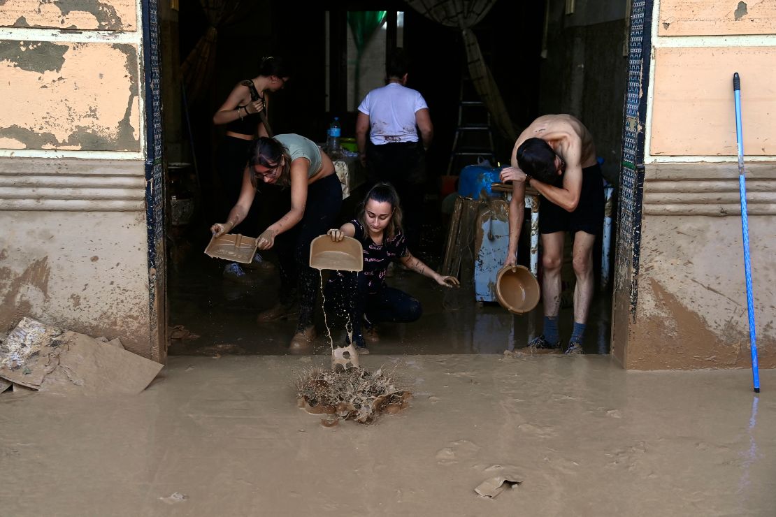 People try to clear mud from a house on October 31, 2024, after flash floods hit La Torre in Valencia, eastern Spain.