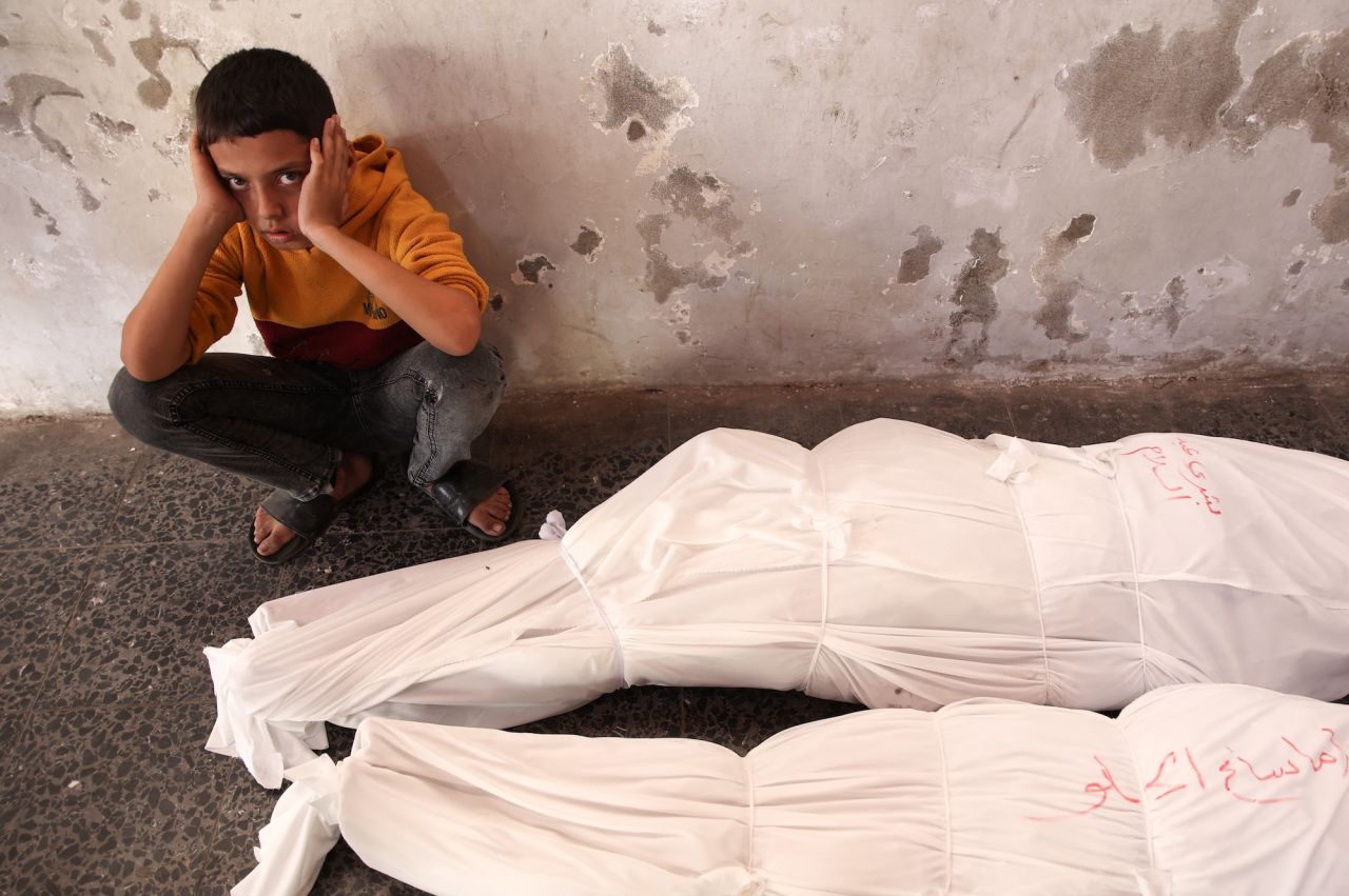 A Palestinian child sits next to the shrouded bodies of people killed in an Israeli strike in northern Gaza on Thursday.