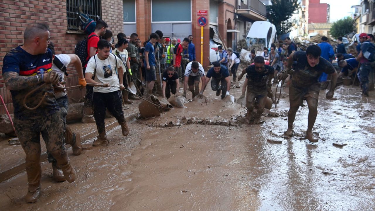 Locals and volunteers remove mudy water, on November 1, 2024, after a flooding devastated the town of Paiporta, in the region of Valencia, eastern Spain. The death toll from Spain's worst floods in a generation has climbed to 205, rescuers said today, with the number expected to rise as more people are believed missing. The agency coordinating emergency services in the eastern Valencia region said 202 people had been confirmed dead there, with officials in Castilla-La Mancha and Andalusia previously announcing a combined three deaths in their regions. (Photo by JOSE JORDAN / AFP) (Photo by JOSE JORDAN/AFP via Getty Images)