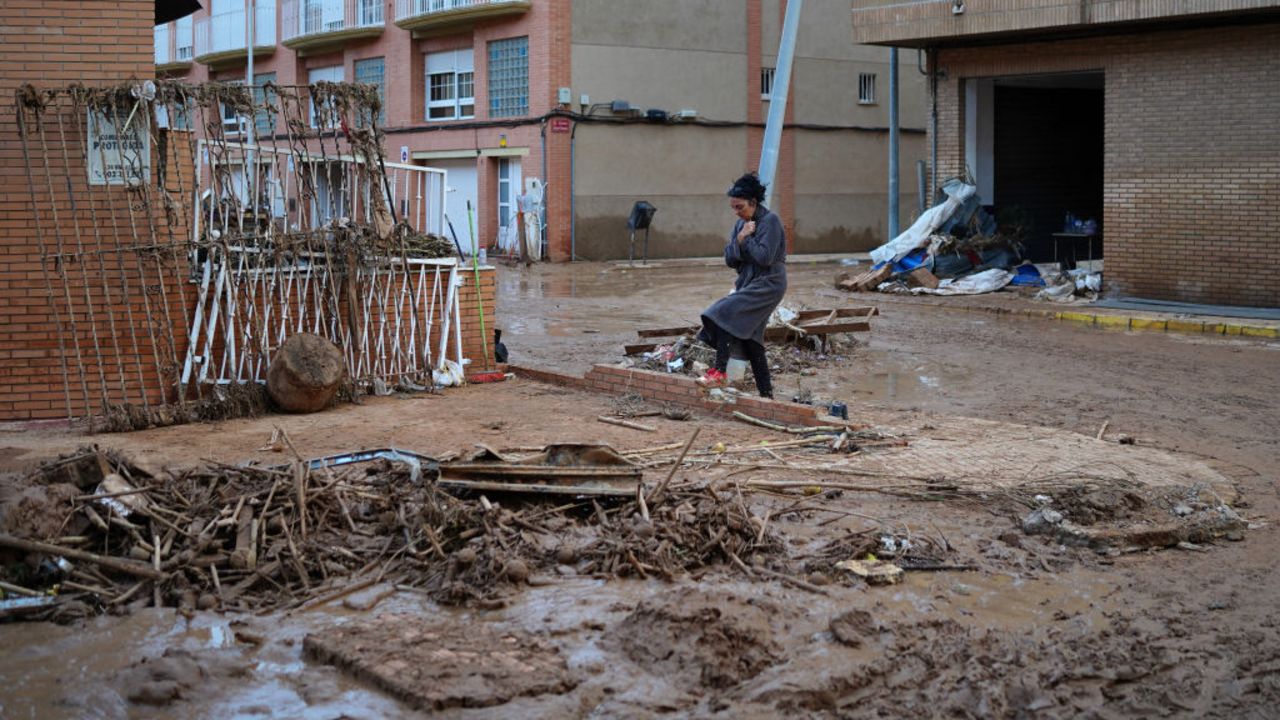 TOPSHOT - A woman in a bathrobe crosses a mud-covered, debris-strewn street, on November 1, 2024, after a flooding devastated the town of Paiporta, in the region of Valencia, eastern Spain. The death toll from Spain's worst floods in a generation has climbed to 205, rescuers said today, with the number expected to rise as more people are believed missing. The agency coordinating emergency services in the eastern Valencia region said 202 people had been confirmed dead there, with officials in Castilla-La Mancha and Andalusia previously announcing a combined three deaths in their regions. (Photo by Manaure Quintero / AFP) (Photo by MANAURE QUINTERO/AFP via Getty Images)