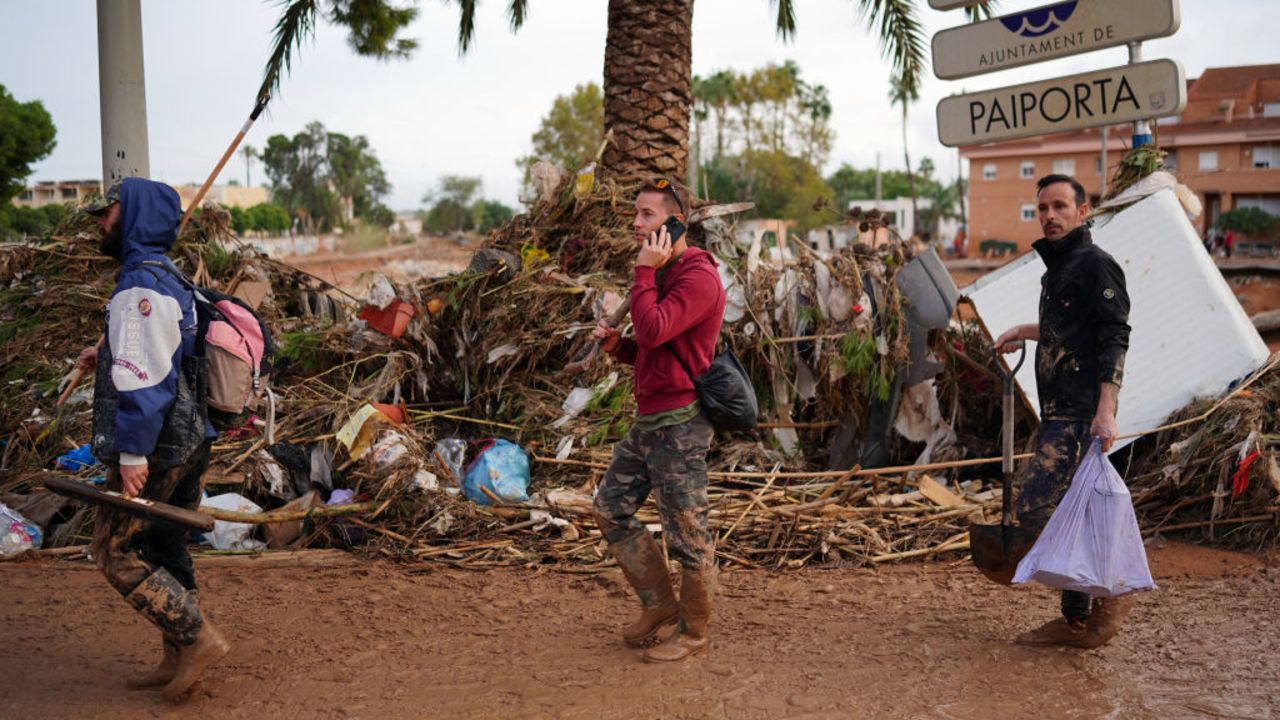 Three people walk on a street covered in mud and debris, on November 1, 2024, after a flooding devastated the town of Paiporta, in the region of Valencia, eastern Spain. The death toll from Spain's worst floods in a generation has climbed to 205, rescuers said today, with the number expected to rise as more people are believed missing. The agency coordinating emergency services in the eastern Valencia region said 202 people had been confirmed dead there, with officials in Castilla-La Mancha and Andalusia previously announcing a combined three deaths in their regions. (Photo by Manaure Quintero / AFP) (Photo by MANAURE QUINTERO/AFP via Getty Images)