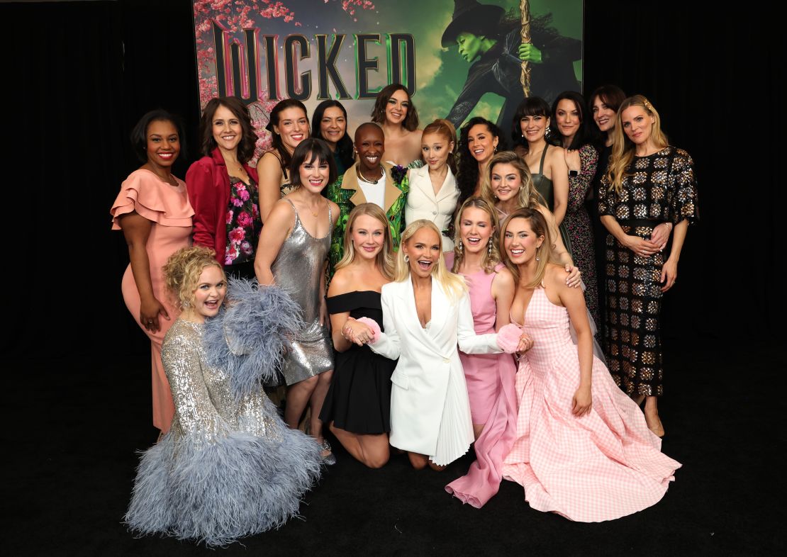 Actresses who have played Glinda previously, including McKenzie Kurtz (front row, far right, in pink gingham), pose at an early screening of the film hosted by Ariana Grande and Cynthia Erivo.