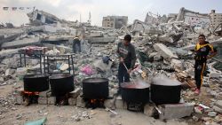 TOPSHOT - A man prepares meals to be distributed to displaced Palestinians in front of a levelled building in Gaza City on November 2, 2024, amid the ongoing war between Israel and Hamas militants. (Photo by Omar AL-QATTAA / AFP) (Photo by OMAR AL-QATTAA/AFP via Getty Images)