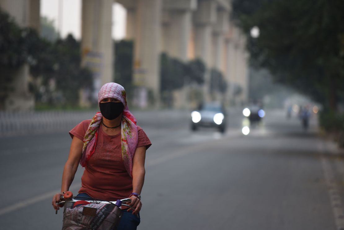 A woman cycles through the smog in Gurgaon, India, on November 2, 2024.