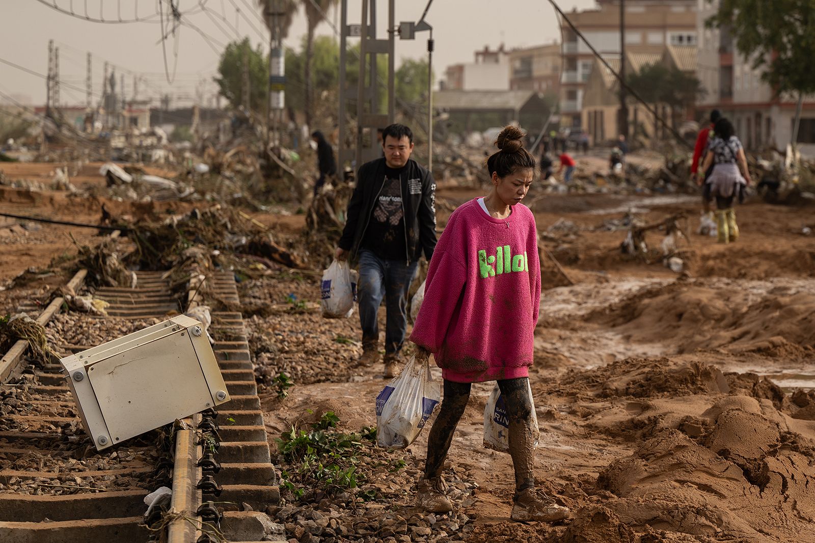 A woman walks along train tracks covered by debris in Valencia.