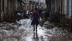 TOPSHOT - A volunteer walks on a muddy street as he leaves Paiporta, in the region of Valencia, eastern Spain, on November 3, 2024, in the aftermath of devastating deadly floods. The death toll from Spain's worst floods in a generation has climbed to 217, rescuers said today. (Photo by JOSE JORDAN / AFP) (Photo by JOSE JORDAN/AFP via Getty Images)