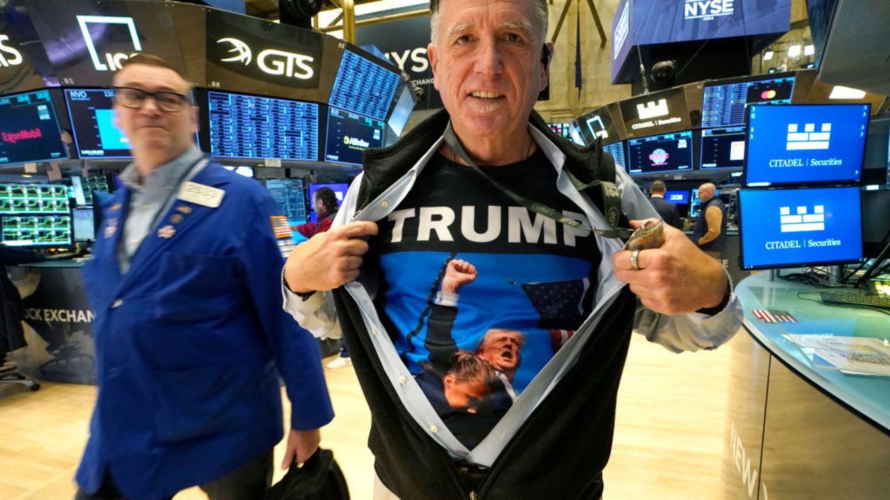 Trader Walter Lundon shows off his shirt featuring US President-elect Donald Trump, on the floor of the New York Stock Exchange (NYSE) in New York City on November 6, 2024. Wall Street stocks surged in opening trading on Wall Street Wednesday after US voters sent Donald Trump back to the White House and delivered him a Republican Senate. Major indices were up 1.8 percent or more in the early going as hopes about expected tax cuts and regulatory easing more than offset worries about higher tariffs. (Photo by TIMOTHY A. CLARY / AFP) (Photo by TIMOTHY A. CLARY/AFP via Getty Images)