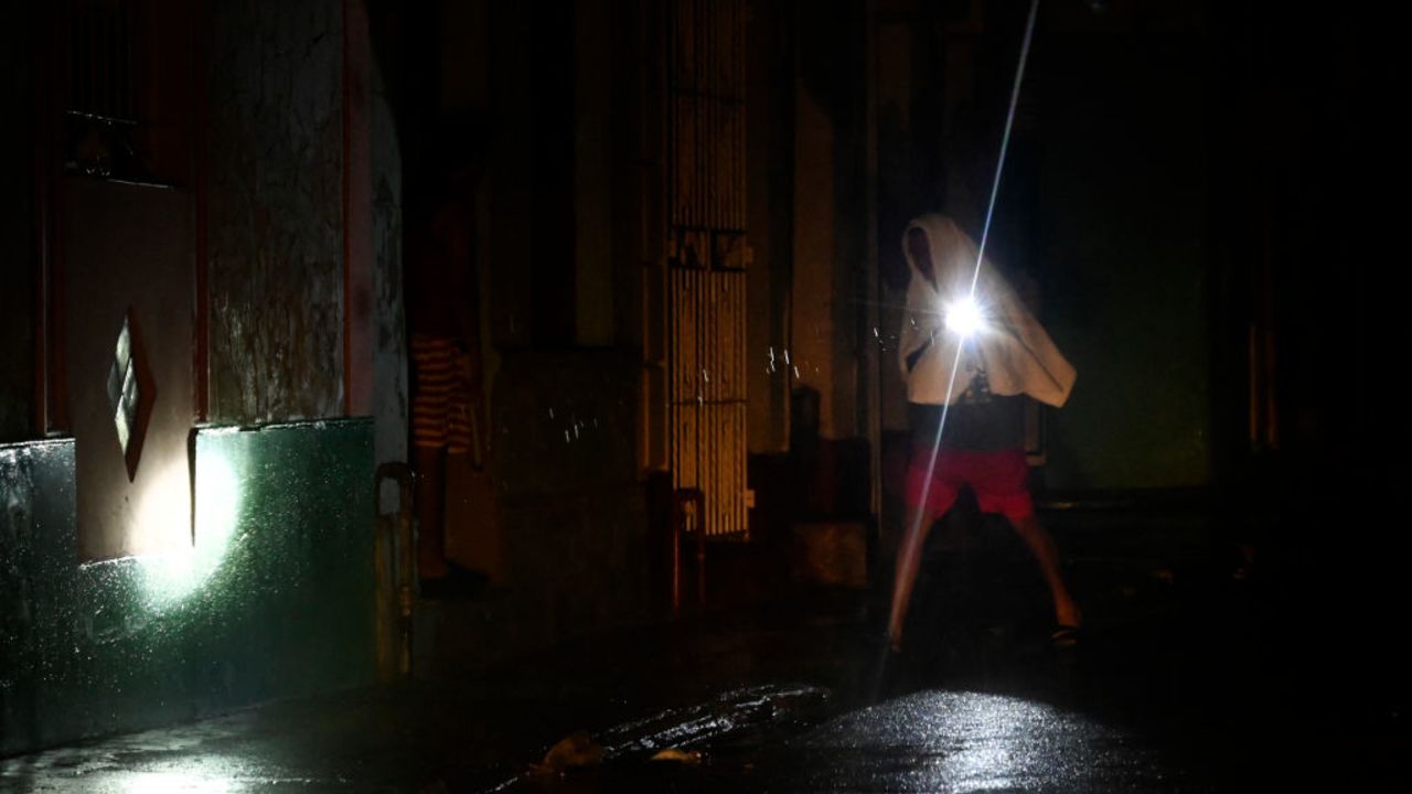 TOPSHOT - A man walks with a torchlight on a darkened street due to a blackout after the pass of hurricane Rafael in Havana, on November 6, 2024. Hurricane Rafael left Cuba on Wednesday night, leaving the island in darkness with widespread power outages and destruction in some villages after hitting as a powerful Category 3 hurricane. (Photo by Yamil LAGE / AFP) (Photo by YAMIL LAGE/AFP via Getty Images)