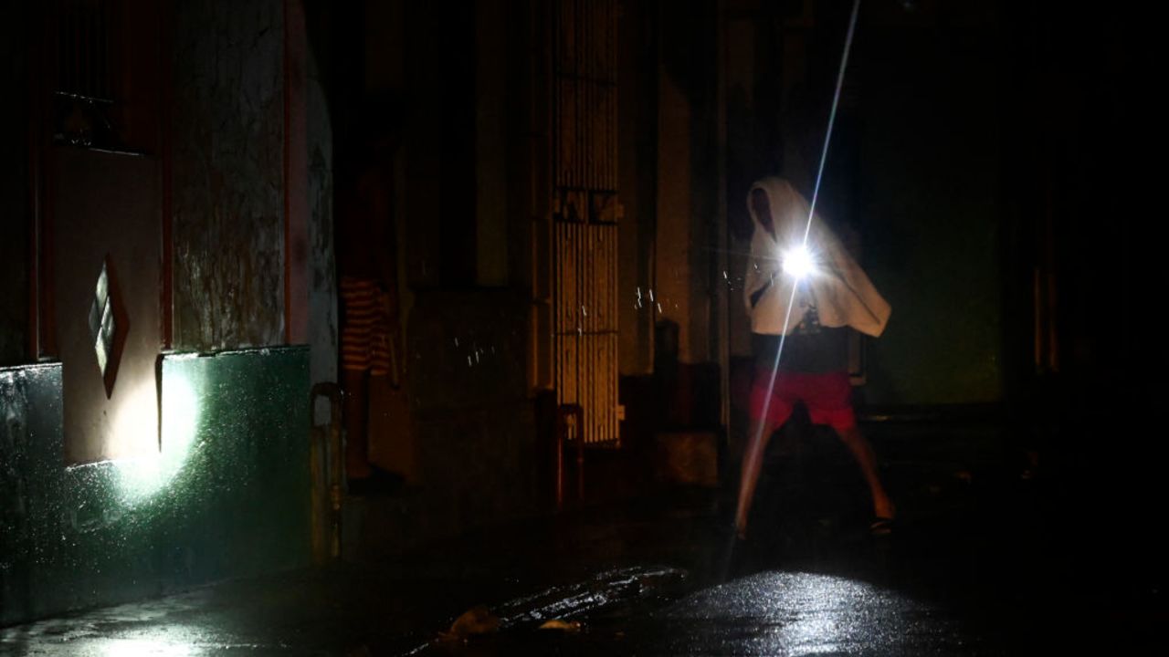 TOPSHOT - A man walks with a torchlight on a darkened street due to a blackout after the of hurricane Rafael in Havana, on November 6, 2024. Hurricane Rafael left Cuba on Wednesday night, leaving the island in darkness with widespread power outages and destruction in some villages after hitting as a powerful Category 3 hurricane. (Photo by Yamil LAGE / AFP) (Photo by YAMIL LAGE/AFP via Getty Images)