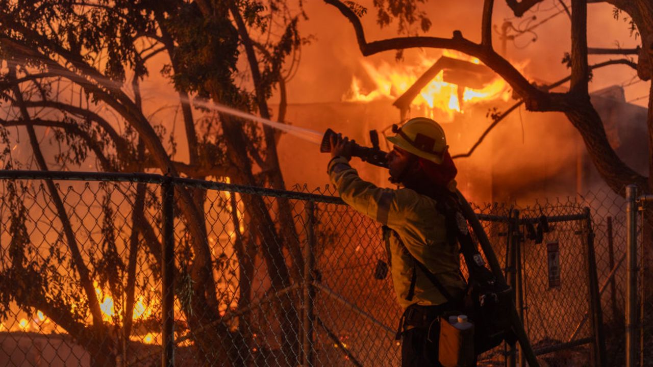 CAMARILLO, CALIFORNIA - NOVEMBER 6: A Los Angeles County firefighter battles flames as a home burns from the Mountain Fire on November 6, 2024 in Camarillo, California. Pushed by strong winds, the fire has burned across more than 10,000 acres since it began this morning.  (Photo by David McNew/Getty Images)