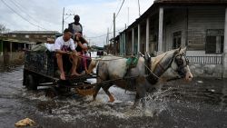 TOPSHOT - People ride on a cart through flooded waters after the passage of hurricane Rafael in Batabano, Artemisa province, Cuba on November 7, 2024. Power was restored to parts of Cuba on Thursday a day after Hurricane Rafael swept over the island, leaving its 10 million inhabitants without electricity for the second time in a month. (Photo by YAMIL LAGE / AFP) (Photo by YAMIL LAGE/AFP via Getty Images)