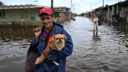 A man walks with his dog through flooded waters after the passage of hurricane Rafael in Batabano, Artemisa province, Cuba on November 7, 2024. Power was restored to parts of Cuba on Thursday a day after Hurricane Rafael swept over the island, leaving its 10 million inhabitants without electricity for the second time in a month. (Photo by YAMIL LAGE / AFP) (Photo by YAMIL LAGE/AFP via Getty Images)