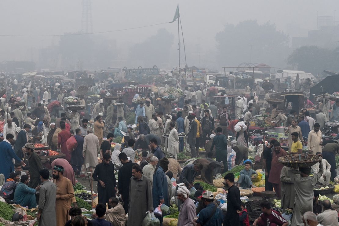 Traders and customers at a wholesale fruit market engulfed in smog in Lahore on November 8, 2024.