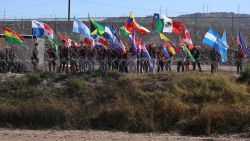 US activists wave flags during a binational mass to remember migrants who have died attempting to reach the US on the banks of the Rio Bravo/Grande on the border of El Paso, Texas, United States, with Ciudad Juarez, Chihuahua State, Mexico, on November 9, 2024. (Photo by HERIKA MARTINEZ / AFP) (Photo by HERIKA MARTINEZ/AFP via Getty Images)