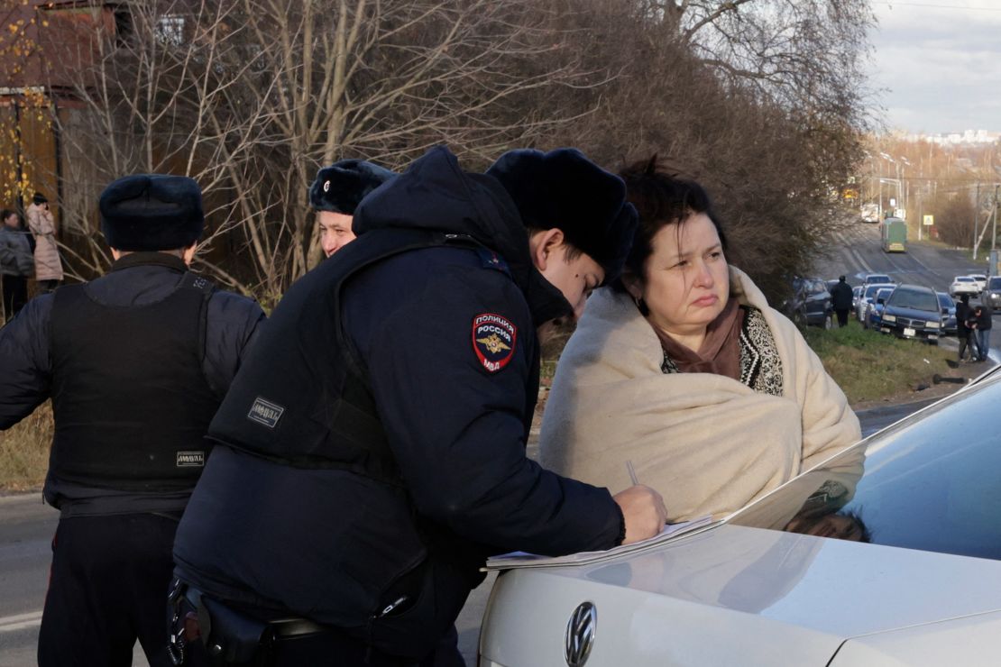 A Russian police officer questions a local resident at site of a drone attack in the village of Stanovoye, Moscow region.