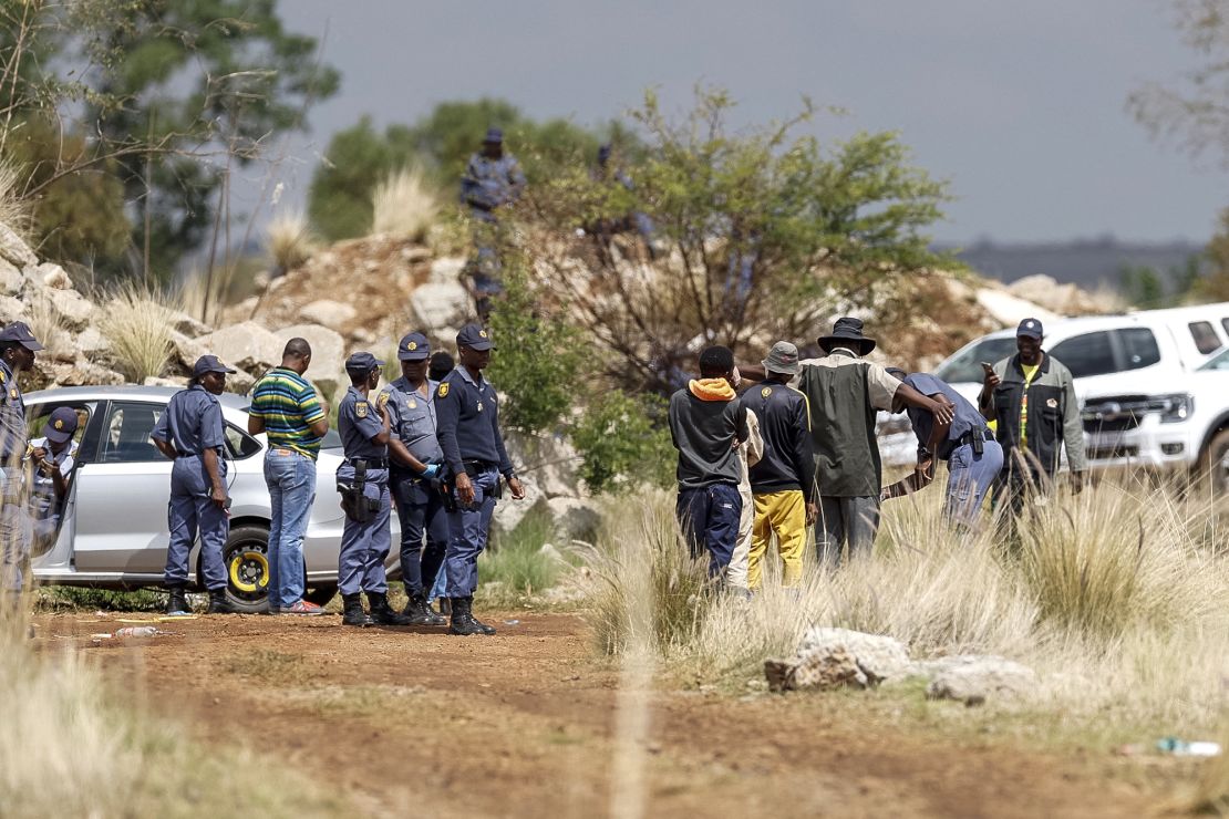 Community members are searched by South African Police Service (SAPS) officers before entering the mine shaft to negotiate with artisanal miners underground to resurface in Stilfontein on November 13, 2024.