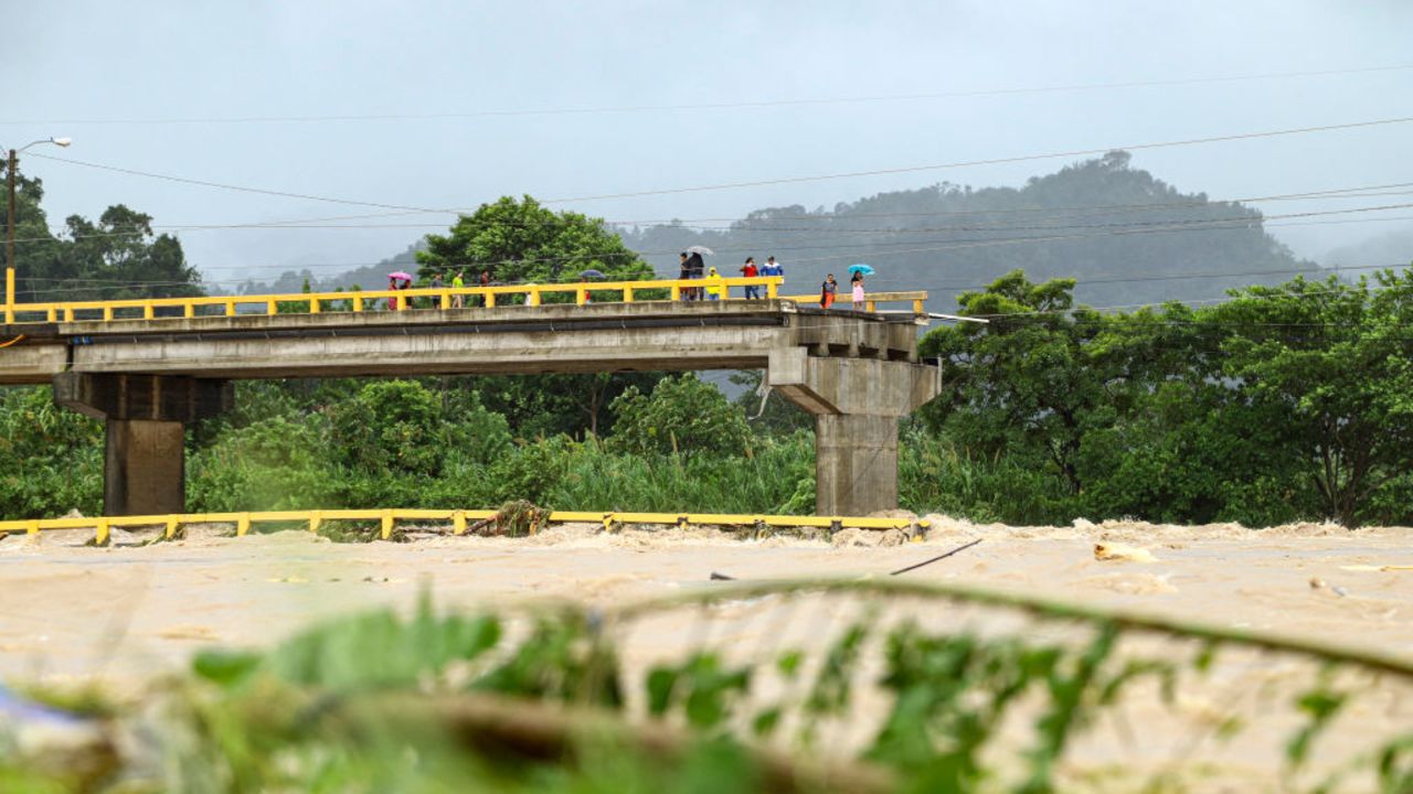 People stand on the destroyed Saopin bridge due to the flooding of the Cangrajal river after the passage of tropical storm Sara in La Ceiba, Honduras, on November 15, 2024. Honduras' President Xiomara Castro said emergency services had been activated to deal with "damage already caused by the rains," warning that Sara's impacts "could become a catastrophic event." (Photo by ESAU OCAMPO / AFP) (Photo by ESAU OCAMPO/AFP via Getty Images)