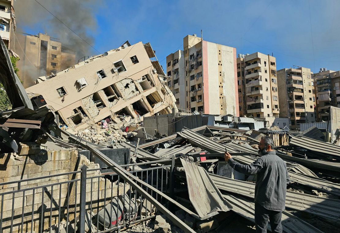 A man watches smoke rising behind a destroyed building following an Israeli airstrike on the district of Haret Hreik in Beirut's southern suburbs on November 16, 2024, amid the ongoing war between Israel and Hezbollah. The strike hit the area shortly after the Israeli army issued a new call to evacuate it.