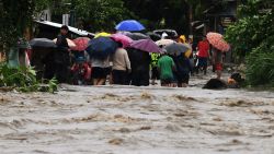 People walk away from the flooded Bermejo river in San Pedro Sula, Honduras, due to the heavy rains left by tropical storm Sara on November 16, 2024. Tropical storm Sara left 45,329 people affected in Honduras, of which more than a thousand have been left homeless or taken to shelters, according to local authorities. (Photo by Orlando SIERRA / AFP) (Photo by ORLANDO SIERRA/AFP via Getty Images)