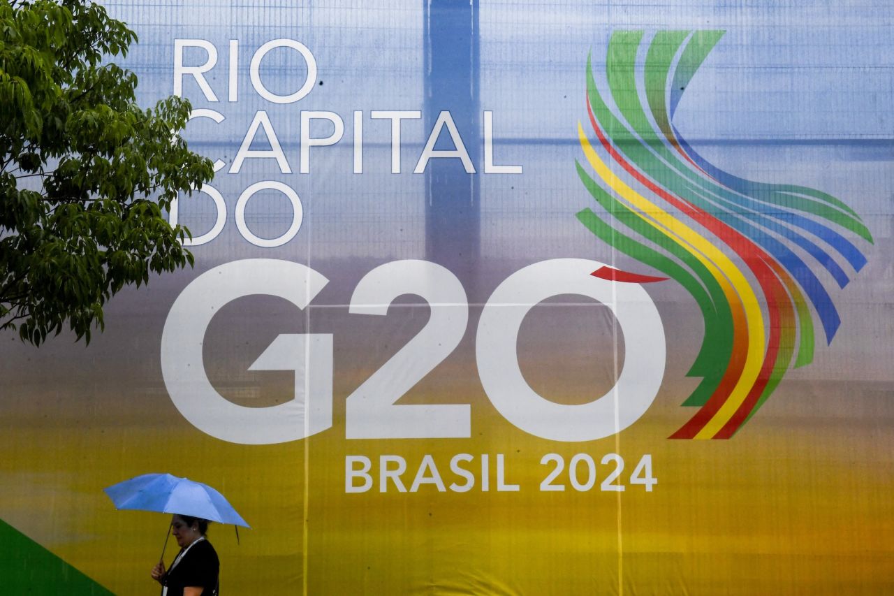 A woman walks carrying an umbrella walks by a G20 Social Summit logo in Rio de Janeiro on November 16.