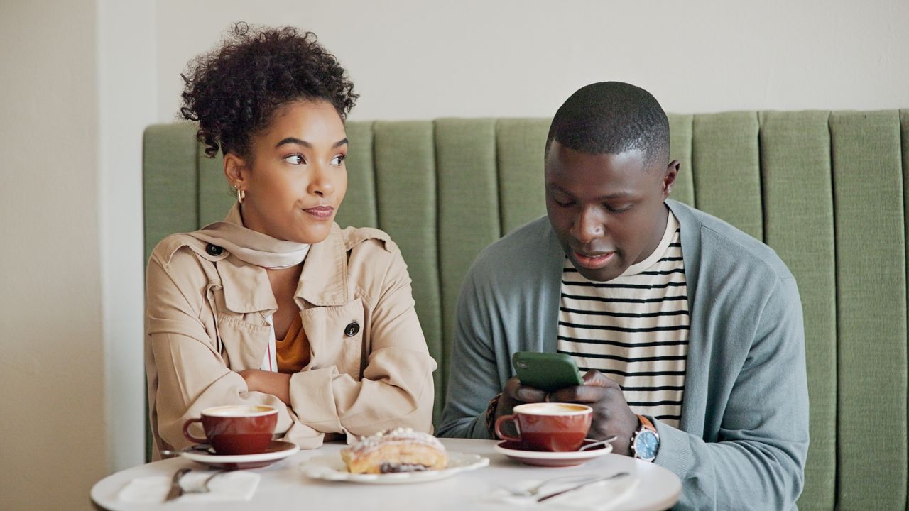 Smartphone, upset and couple in cafe, date and emotions with social media, cappuccino and distracted. Interracial, man and woman in coffee shop, mobile user and cellphone with network, tea and angry