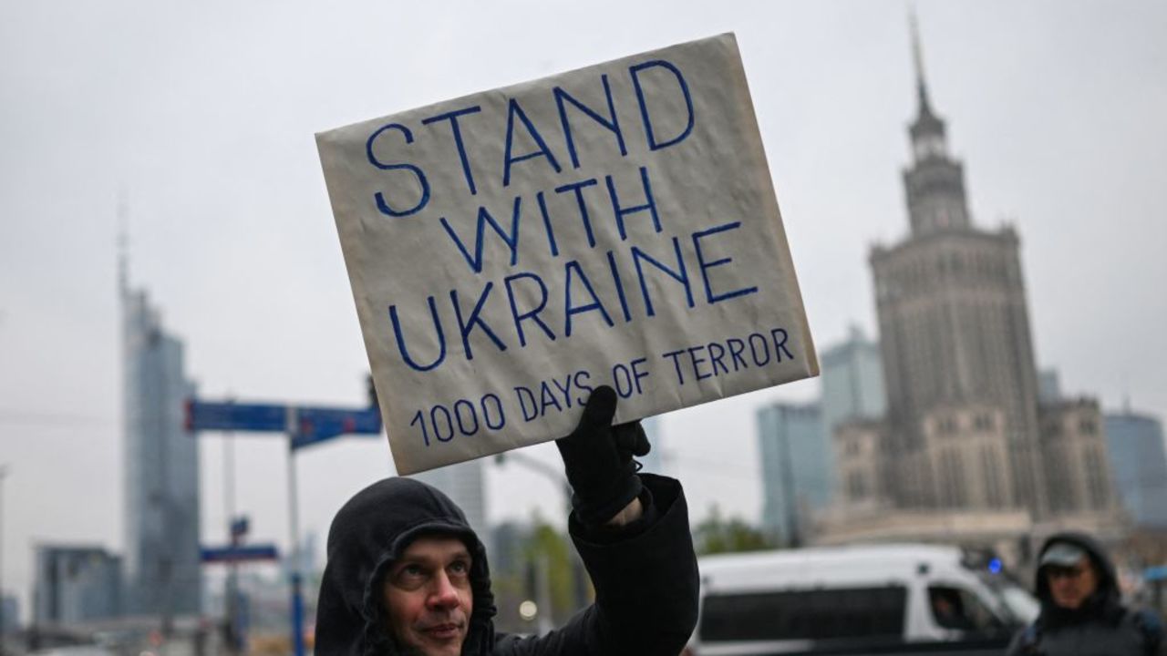 A member of the Russian diaspora holds up a placard with the lettering 'Stand with Ukraine' during a rally in of Ukraine to commemorate 1000 days of the Russian invasion of Ukraine in Warsaw on November 17, 2024. (Photo by Sergei GAPON / AFP) (Photo by SERGEI GAPON/AFP via Getty Images)