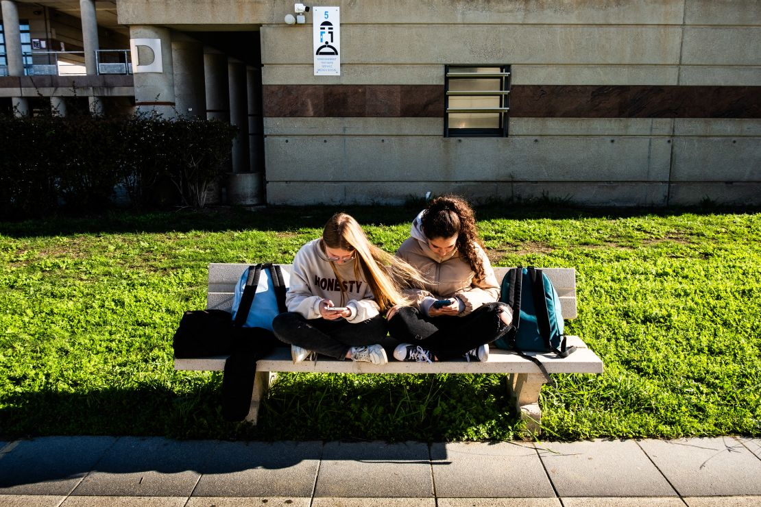 Adolescentes y estudiantes de secundaria sentadas en un banco durante el recreo, consultando sus teléfonos y redes sociales juntas en el Liceo Aristide Maillol de Perpiñán, en los Pirineos Orientales, al sur de Francia, el 14 de noviembre de 2024.