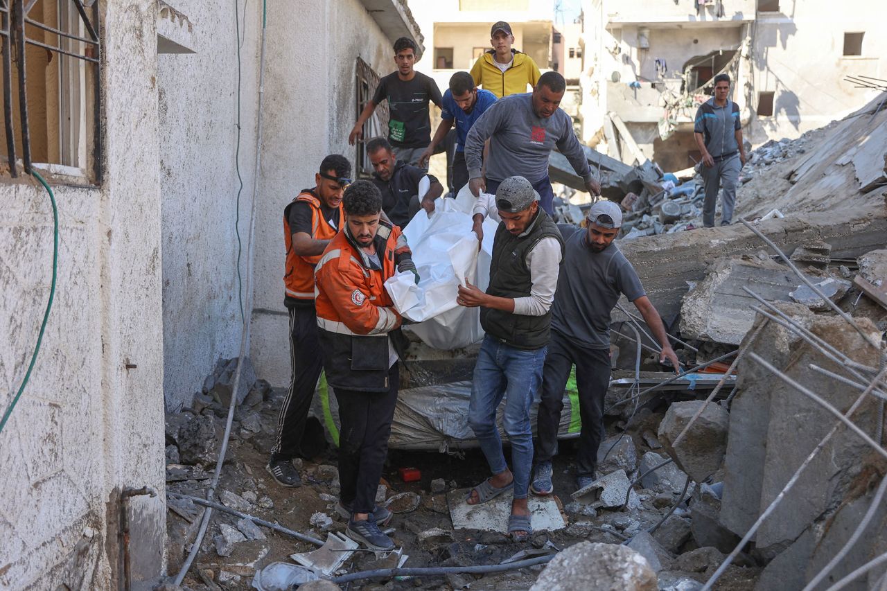 People and rescures carry the covered body of a preson pulled from the rubble of a house destroyed in an Israeli strike on al-Jalaa street in central Gaza City on November 18.