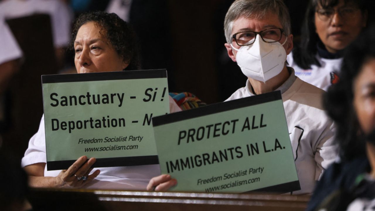 People in the audience hold up signs in support of immigrants as the Los Angeles City Council considers a "sanctuary city" ordinance during a meeting at City Hall in Los Angeles, California, on November 19, 2024. The proposed sanctuary city ordinance would prohibit any city resources from being used  to help federal enforcement of immigration laws. (Photo by Etienne Laurent / AFP) (Photo by ETIENNE LAURENT/AFP via Getty Images)