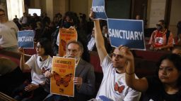 Personas durante una audiencia levantan carteles en apoyo a los inmigrantes mientras el Concejo Municipal de Los Ángeles considera una ordenanza de "ciudad santuario" durante una reunión en el Ayuntamiento de Los Ángeles, California, el 19 de noviembre de 2024. Crédito: ETIENNE LAURENT/AFP/Getty Images