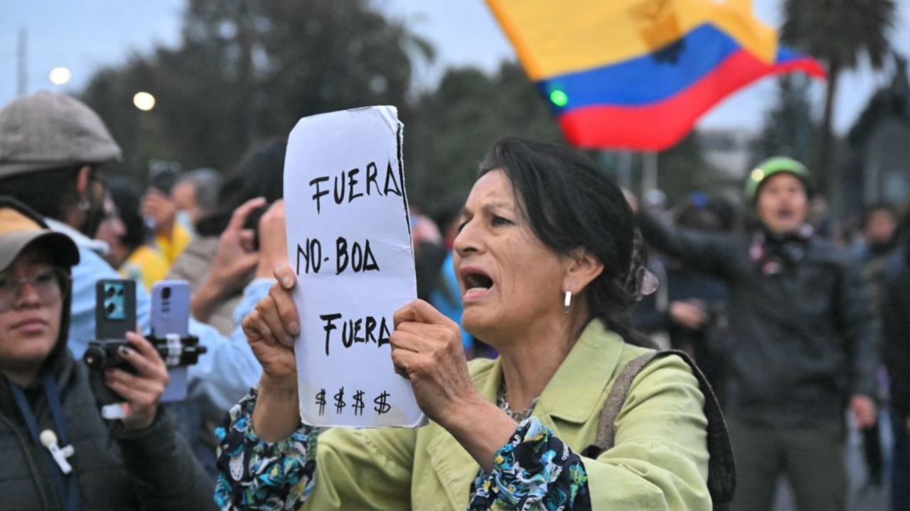 A woman holds a sign reading "Out Noboa" during a protest called by unions and social organizations against Daniel Noboa's government in downtown Quito on November 21, 2024. Drug-related violence, political turmoil, a faltering economy and blackouts lasting up to 14 hours a day mark the run-up to Ecuador's February presidential elections, in which President Daniel Noboa is seeking re-election. (Photo by Rodrigo BUENDIA / AFP) (Photo by RODRIGO BUENDIA/AFP via Getty Images)