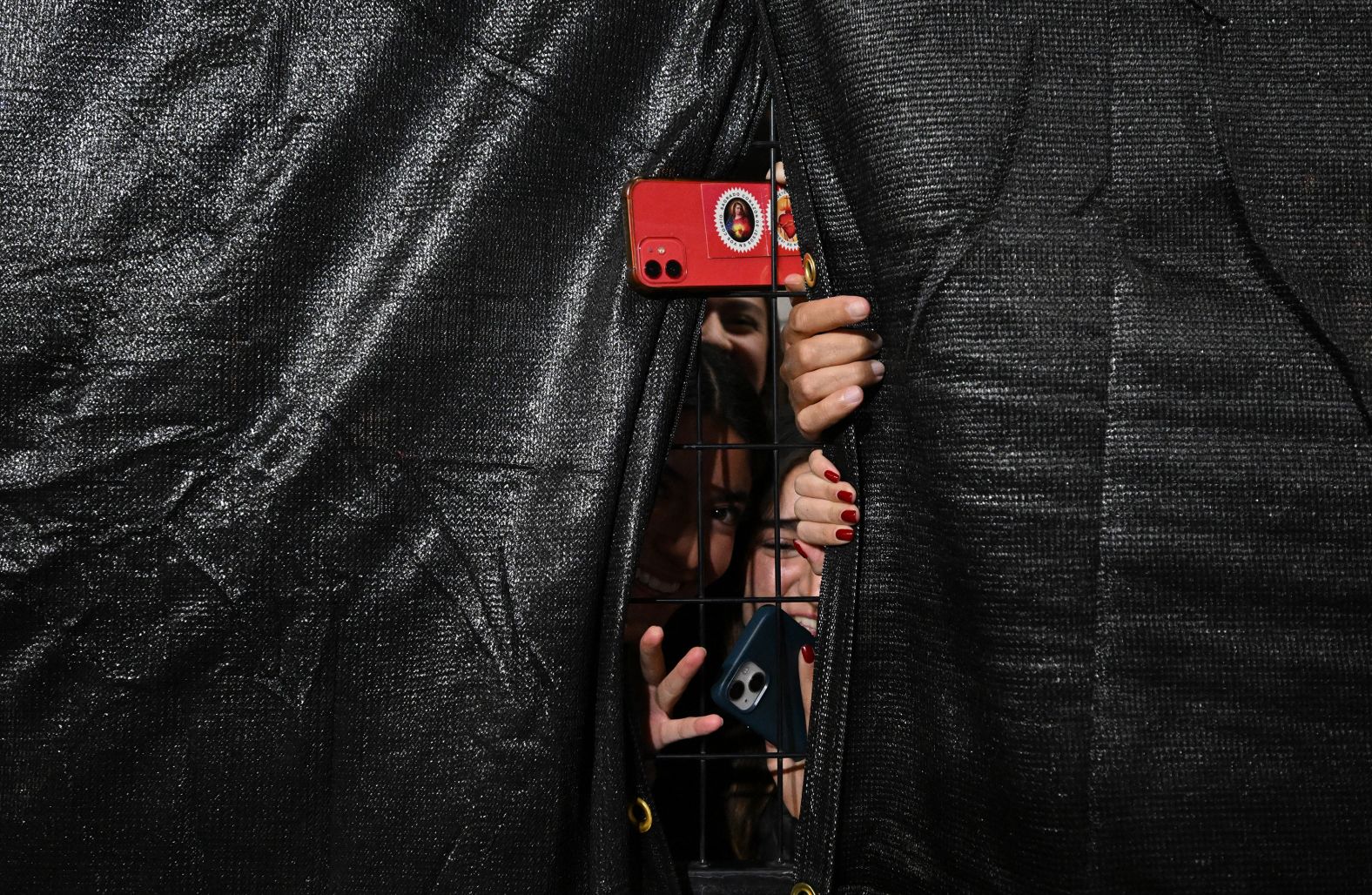 TOPSHOT - Fans take pictures through a fence during the second practice session for the Las Vegas Formula One Grand Prix in Las Vegas, Nevada on November 21, 2024. (Photo by Patrick T. Fallon / AFP) (Photo by PATRICK T. FALLON/AFP via Getty Images)