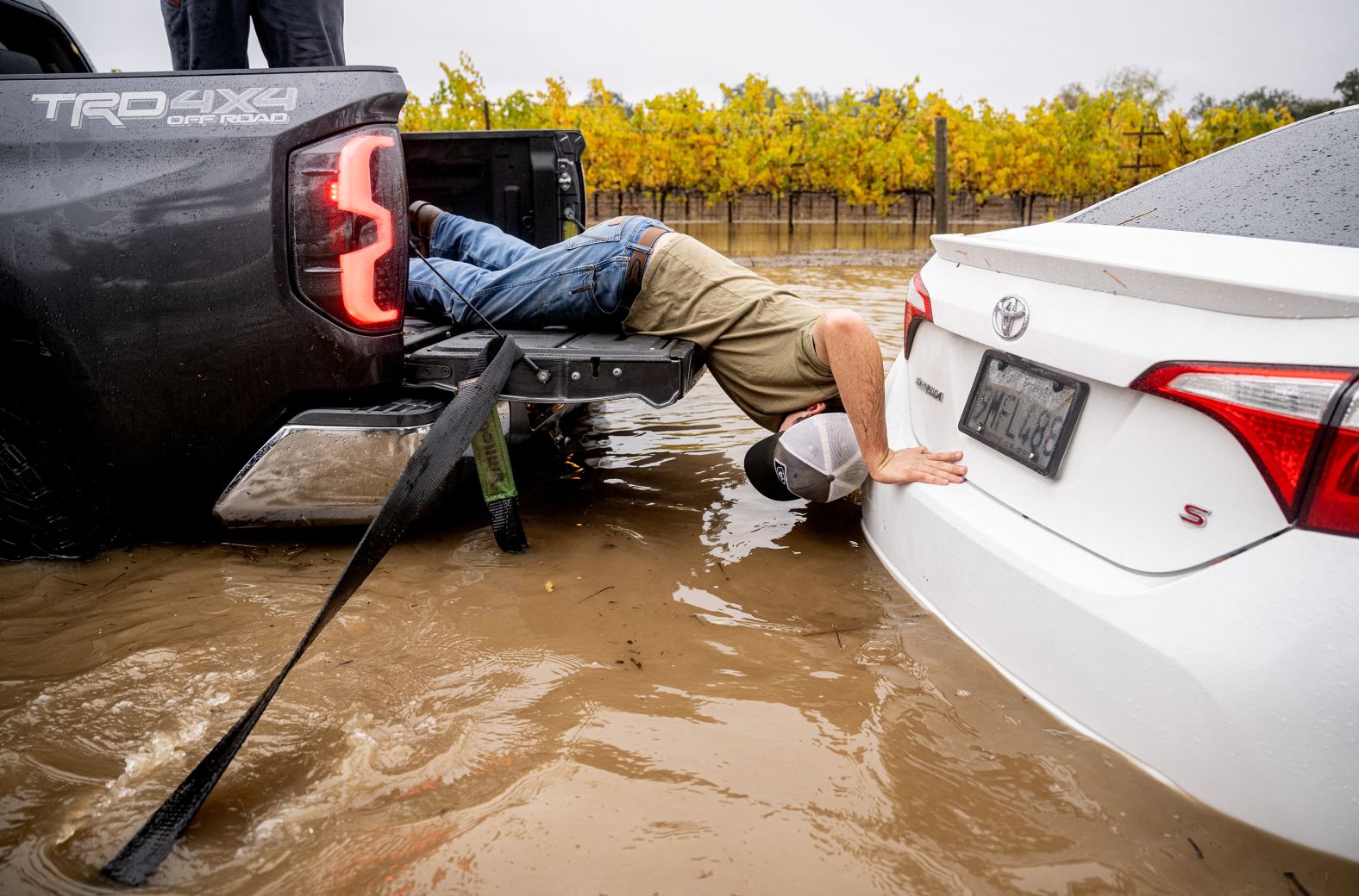 Gabe Sitton assists a stuck driver with her flooded car on Slusser Road in Windsor, California on November 22, 2024. A bomb cyclone has been wreaking havoc on the west coast bringing flooding and winds throughout the region. (Photo by JOSH EDELSON / AFP) (Photo by JOSH EDELSON/AFP via Getty Images)