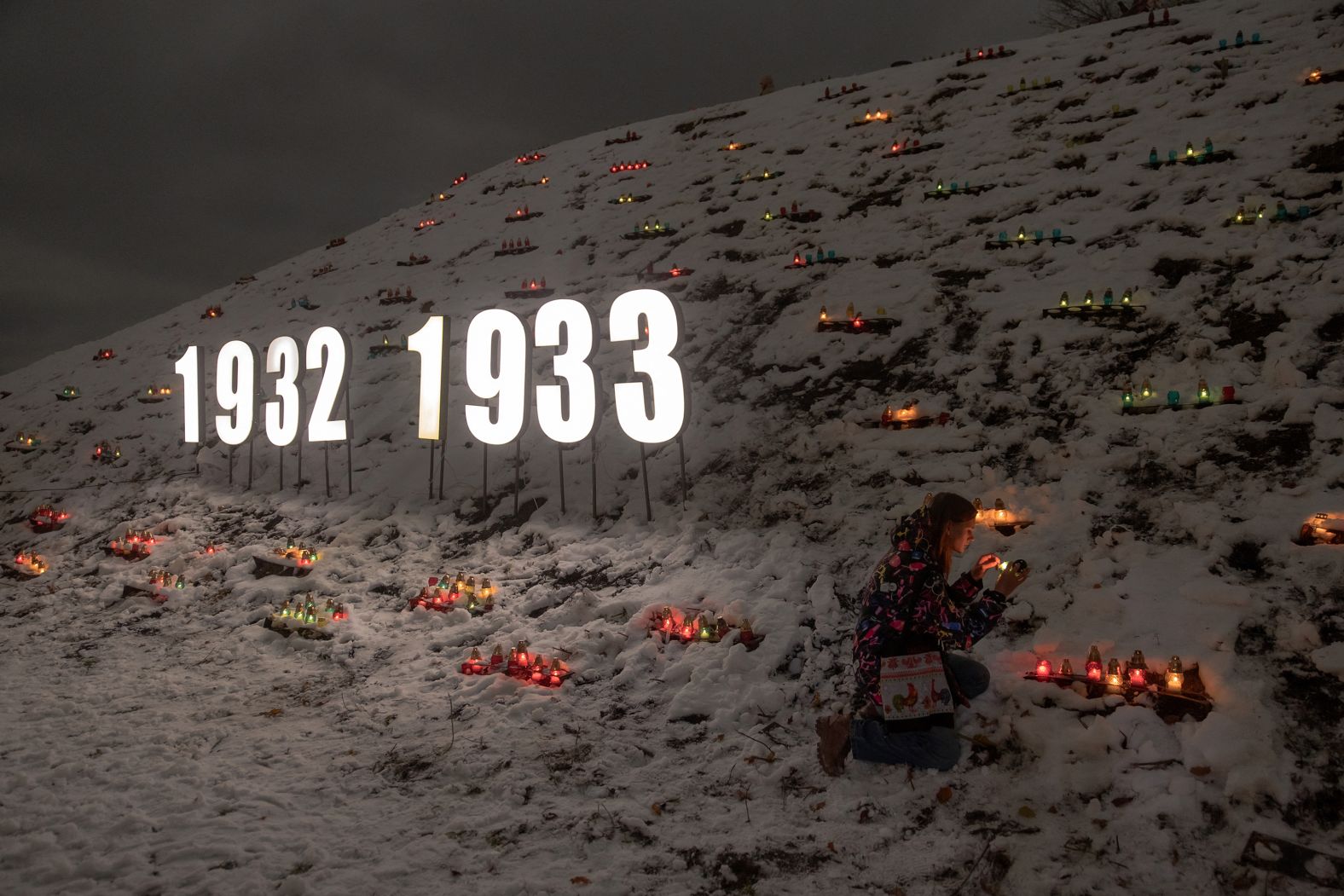 TOPSHOT - A woman lights a candle placed in a lantern in tribute to the victims of the famine of 1932-1933 at the National Museum of the Holodomor-Genocide in Kyiv, on November 23, 2024, amid the Russian invasion of Ukraine. Ukraine marked 91 years since the Stalin-era Holodomor famine, one of the darkest moments in its history that left millions dead. (Photo by Roman PILIPEY / AFP) (Photo by ROMAN PILIPEY/AFP via Getty Images)